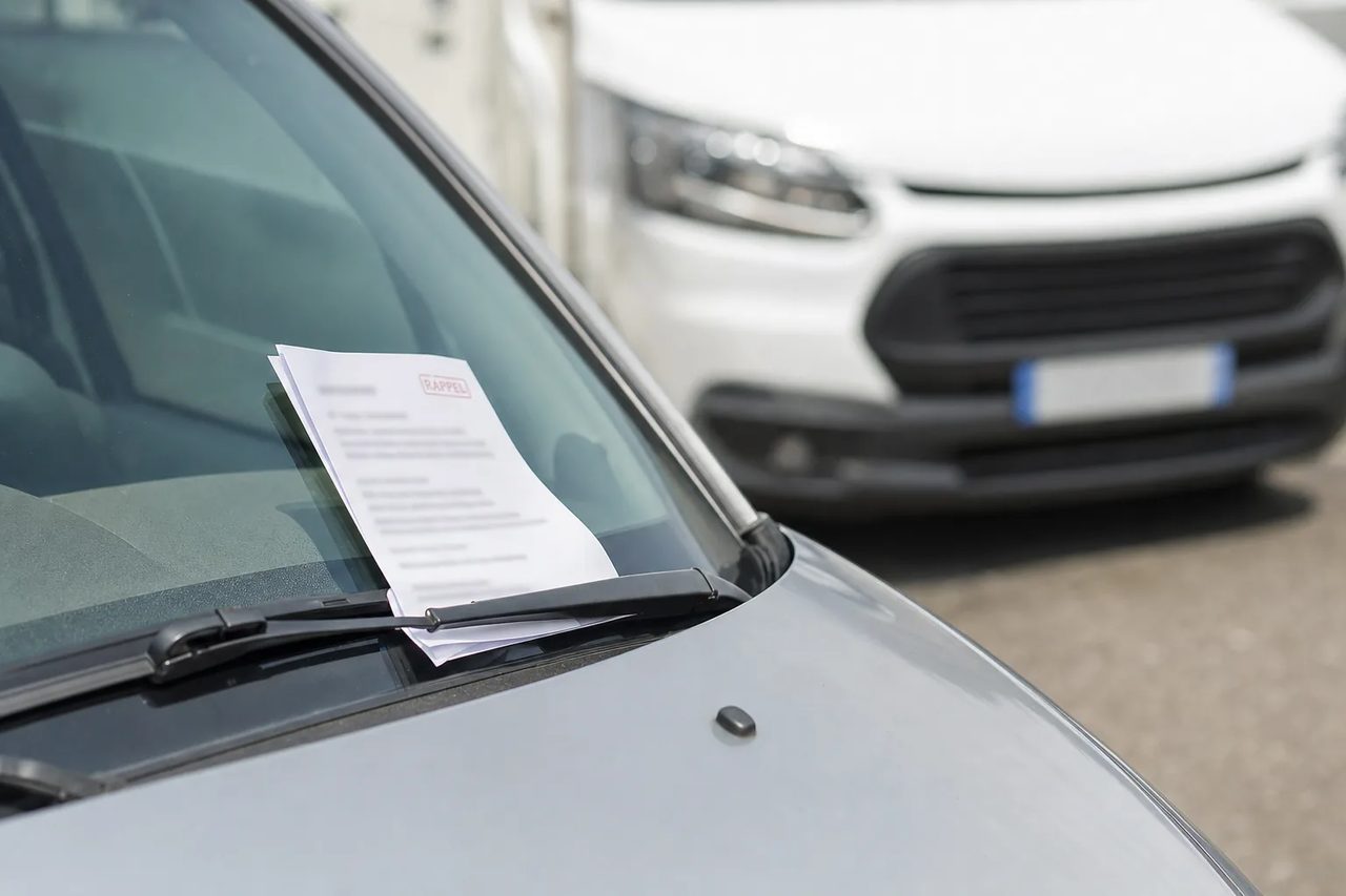 Avis de stationnement glissé sous l'essuie-glace d'une voiture stationnée