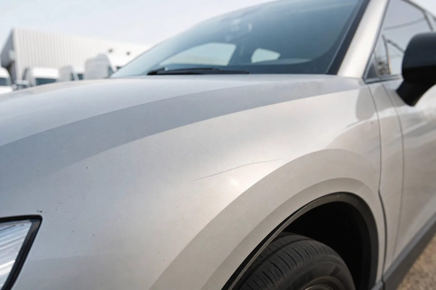 Aile avant d'une voiture propre montrant une fine rayure en lumière rasante