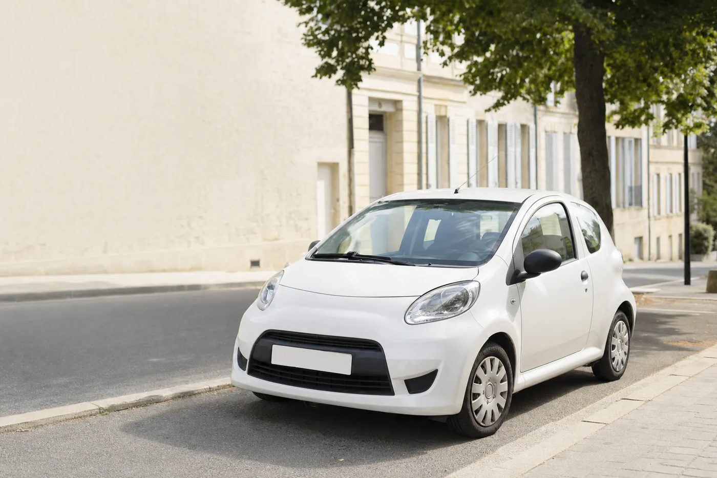 Petite citadine blanche stationnée le long d'une rue résidentielle française