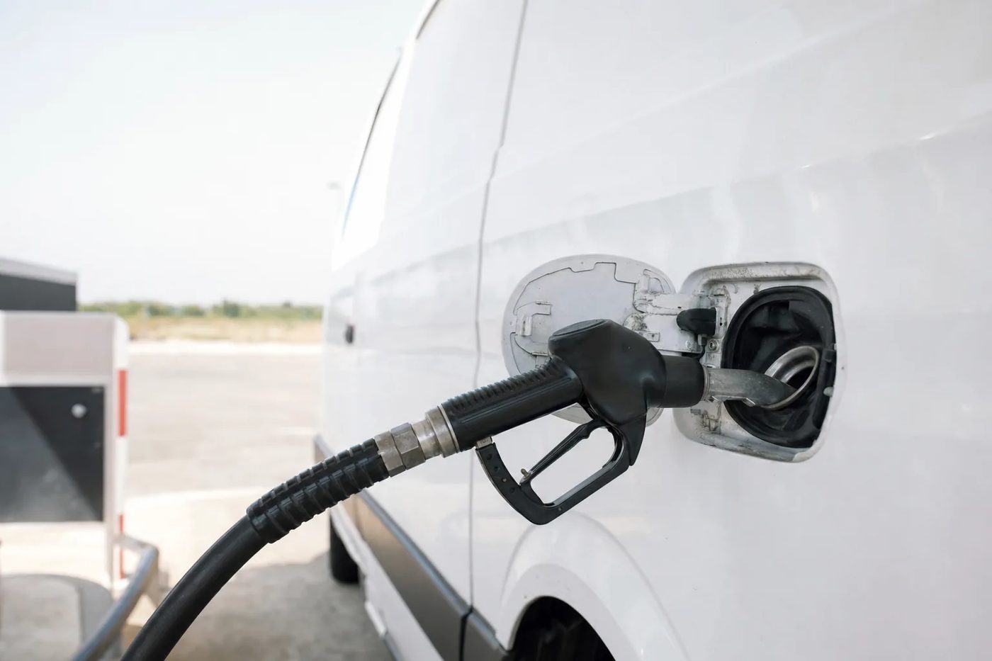 Pistolet de pompe à carburant inséré dans le réservoir d'un utilitaire blanc